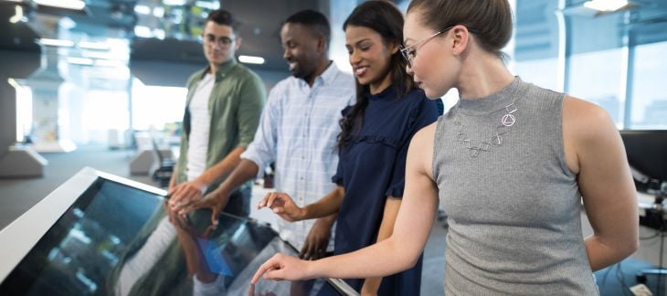 Four people showing how to manage digital signage.