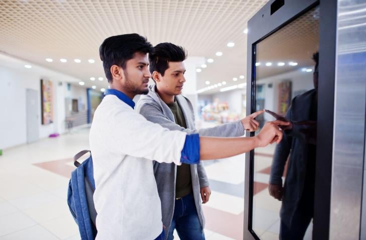 Men interacting with a touchscreen digital display.