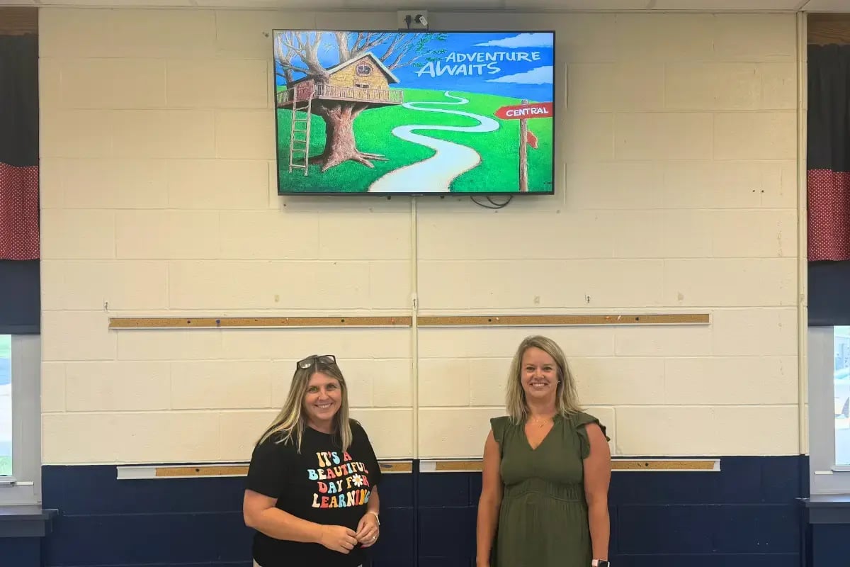two females in front of a wall with digital signage