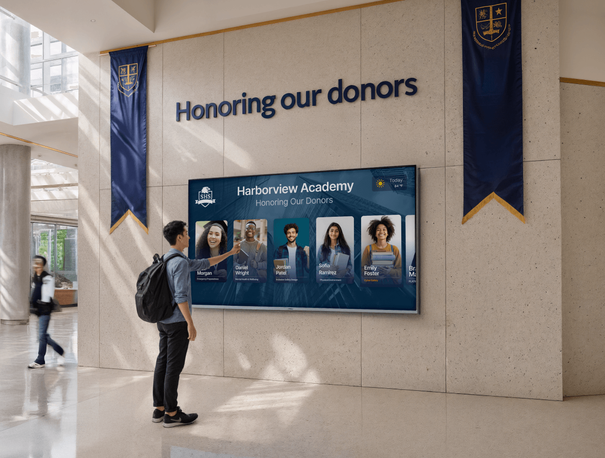 A male university student interacting with a digital donor wall display