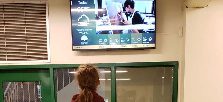 George School case study student watching digital signage in hallway.