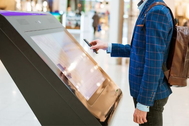 A guy using touchscreen digital signage in a shopping mall.