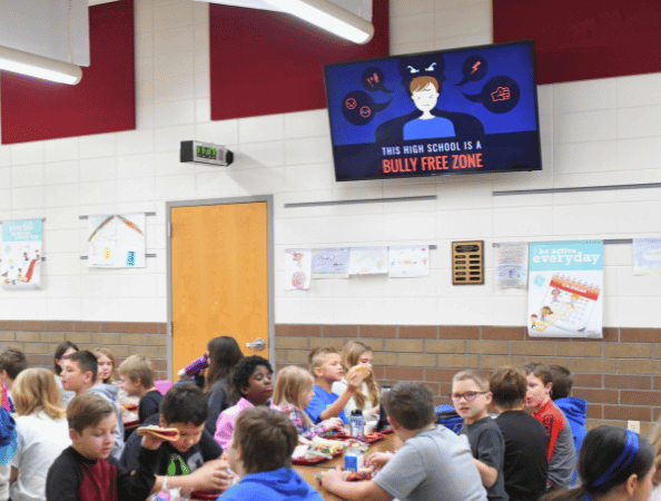 Digital display in a school cafeteria with children that says "Bully Free Zone"