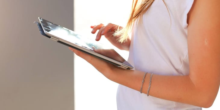 A woman holding a tablet, symbolizing the accessibility of digital signage solutions for reaching everyone in the organization, promoting inclusivity and effective communication strategies.