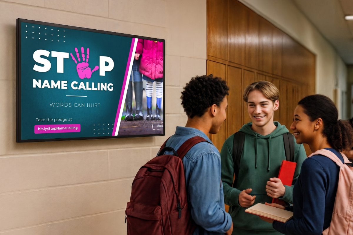 3 middle-school students standing in front of a digital display showing anti-bullying content