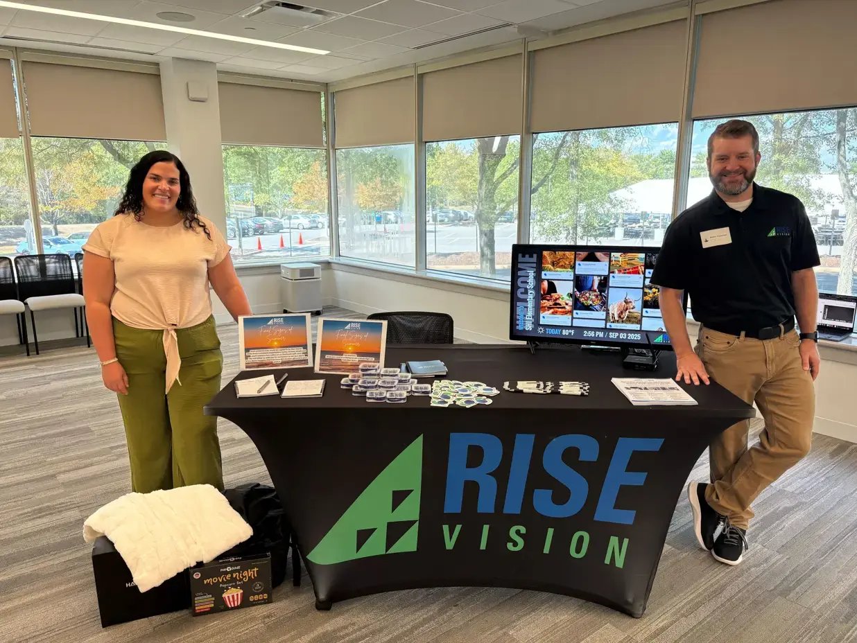 Rise Vision team standing at a reseller event with a booth