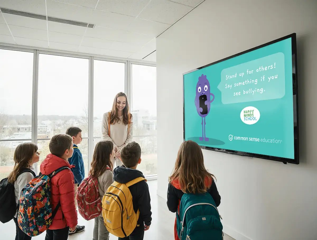 Young students standing in front of a TV display with digital signage