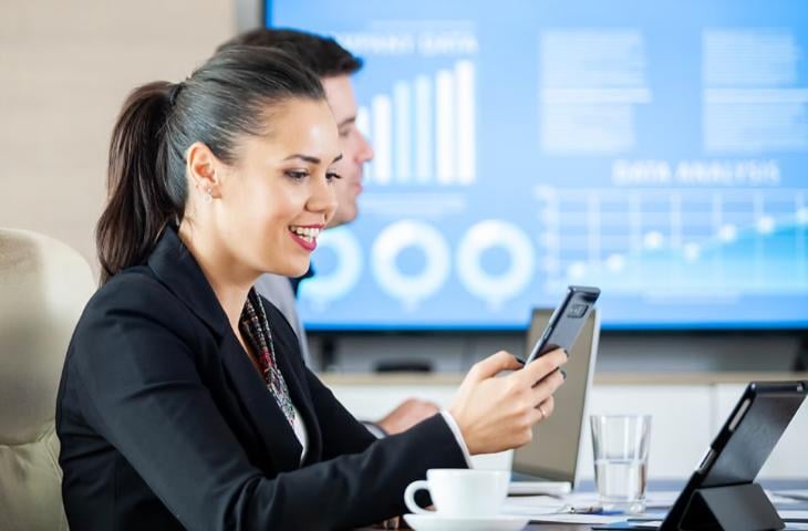 An office woman scanning a tablet with AR during a company meeting.