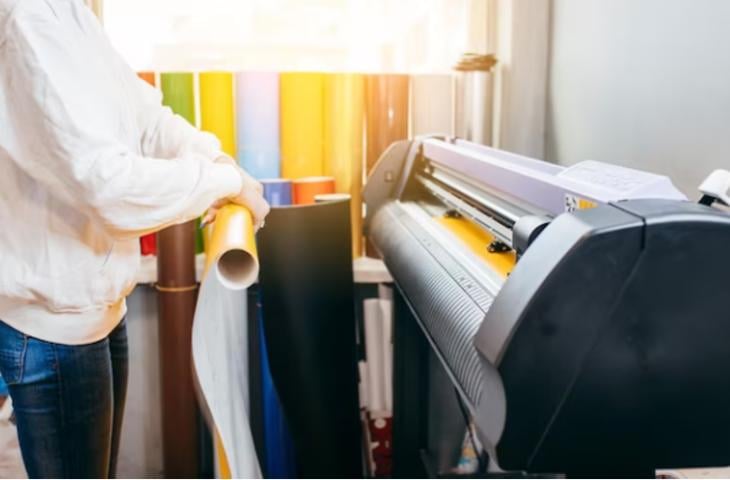 A woman printing an ad poster in a commercial printer.
