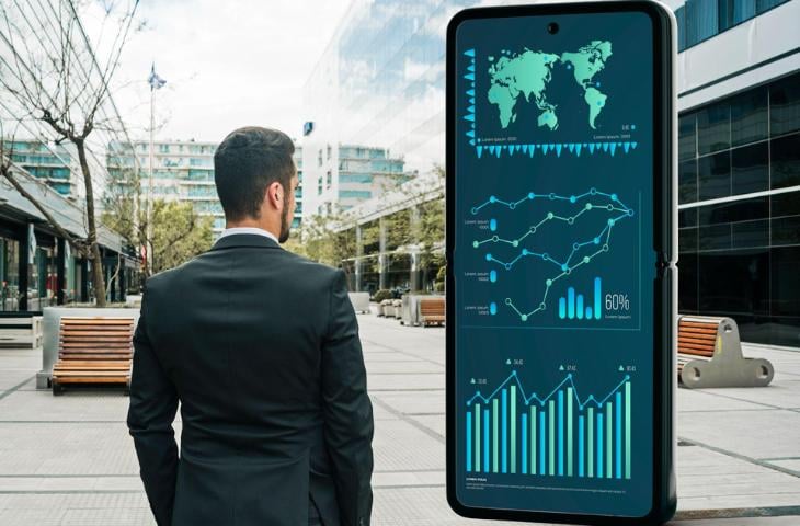 A man standing in front of a digital signage screen showing collected data.