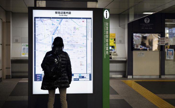 A woman looking at a map on a digital signage screen.