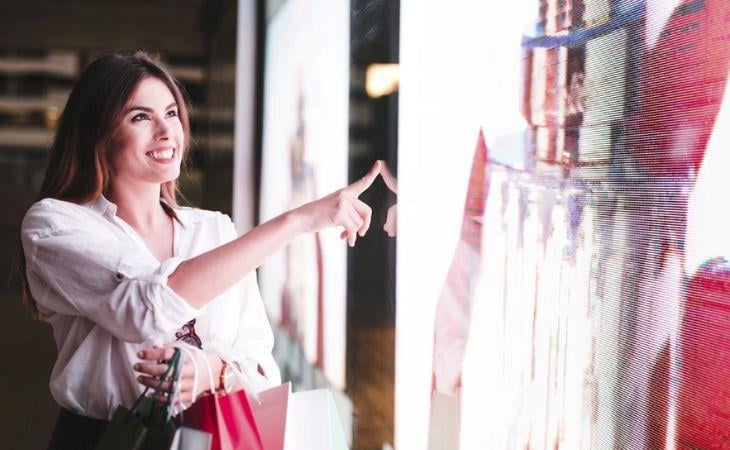 A woman looking at a digital signage screen showing content with good background contrast.