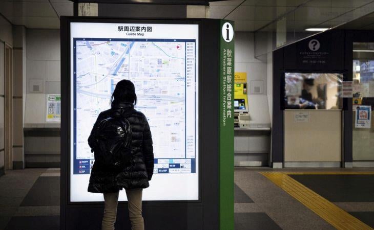 A passenger looking at a guide map on a digital signage screen.