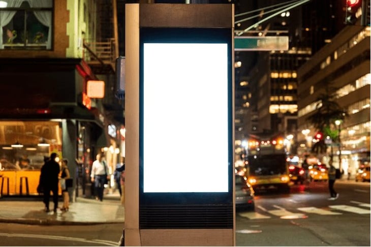 Digital signage screen lit up at night on a sidewalk. 