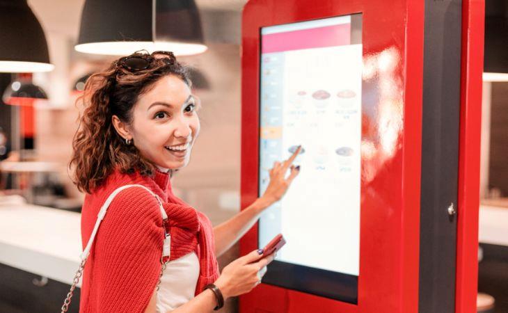 A woman interacting with digital signage inside a local coffee shop.