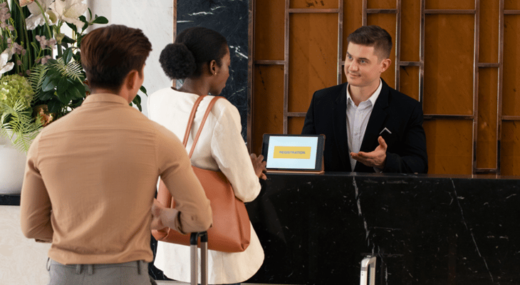 Hotel front desk asking guests to register on a digital sign.