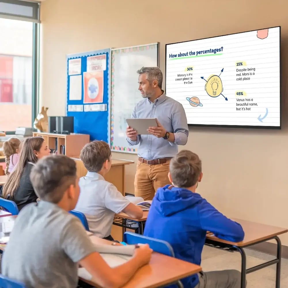 Male teacher in a classroom setting using a digital signage display