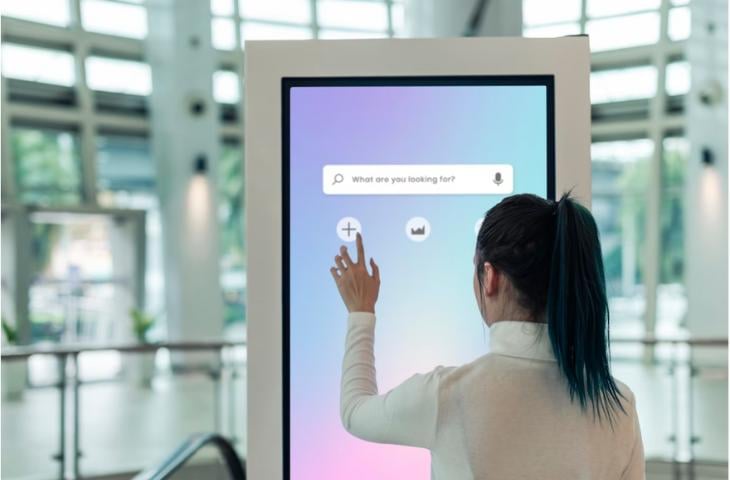 A woman navigating an interactive digital signage screen.