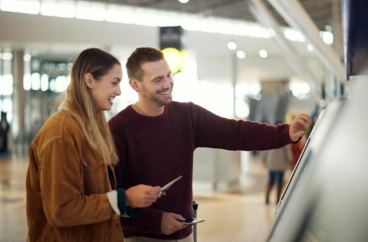 A couple happily interacting with a digital signage screen.