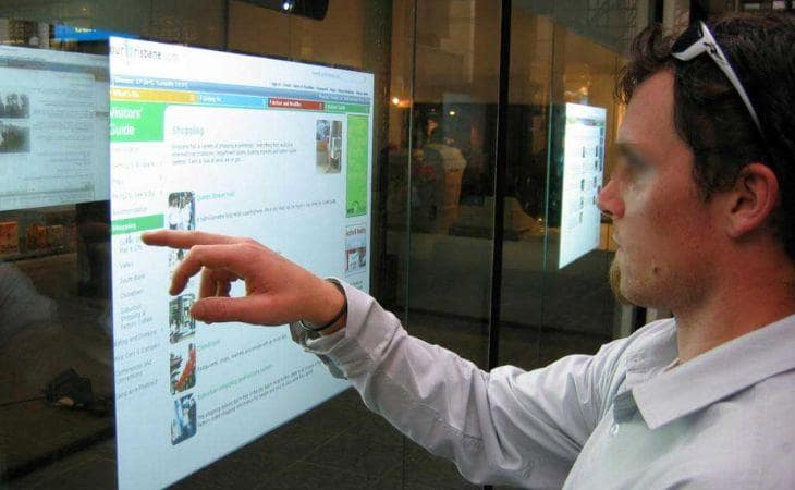 A man Interacting with an enterprise digital signage touch screen.