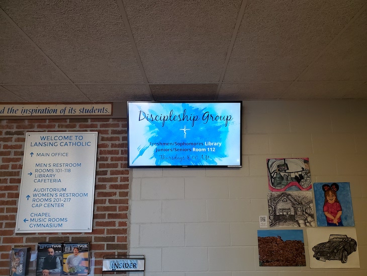 Digital signage at Lansing Catholic High School showing a Discipleships Group event flyer