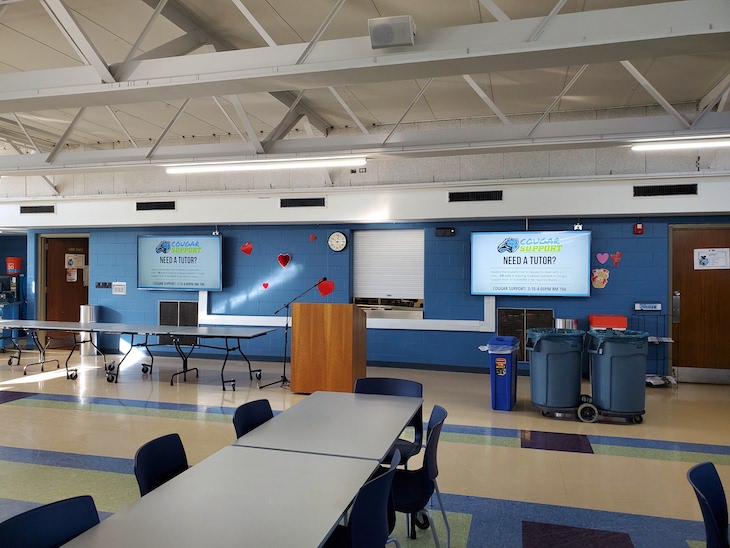 Digital signage at Lansing Catholic High School showing "Need a Tutor?" messages