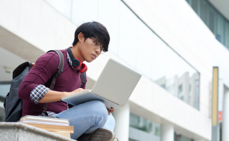 male student researching using laptop