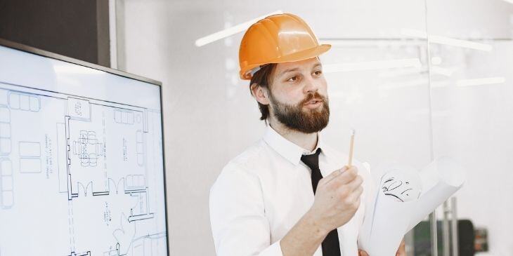 A man explaining a manufacturing dashboard display in the office.