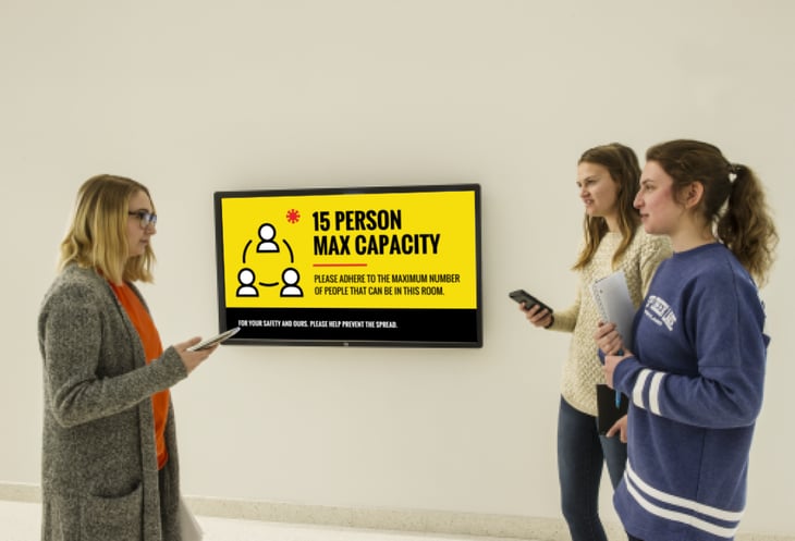 A group standing in front of a display explaining the maximum building occupancy