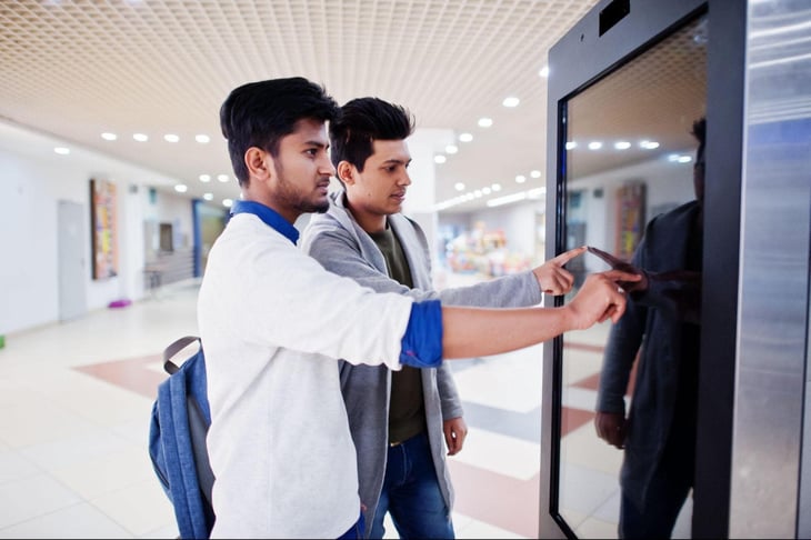 Two men interacting with a digital sign. 