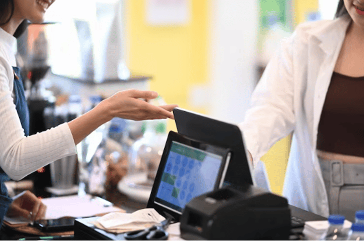 A customer interacting with a DOOH screen at a store’s checkout counter.