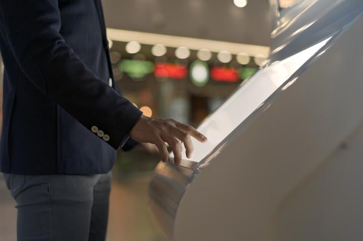 A man interacting with a touchscreen kiosk at the mall.