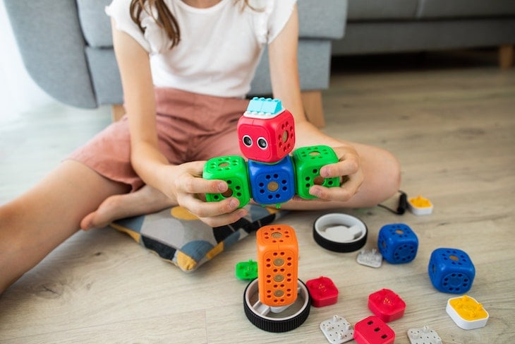 A girl in white shirt with stem activities blue and red car toy