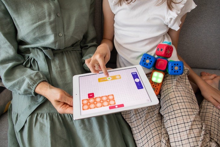 Child playing a game in STEM classes coding on white ipad