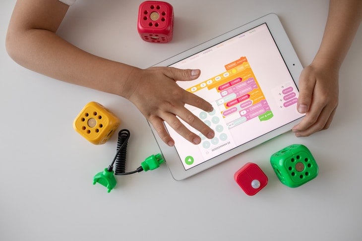 Person learning STEM holding a white ipad visual programming