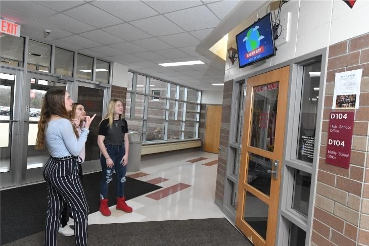 students looking at electronic bulletin board showing digital event