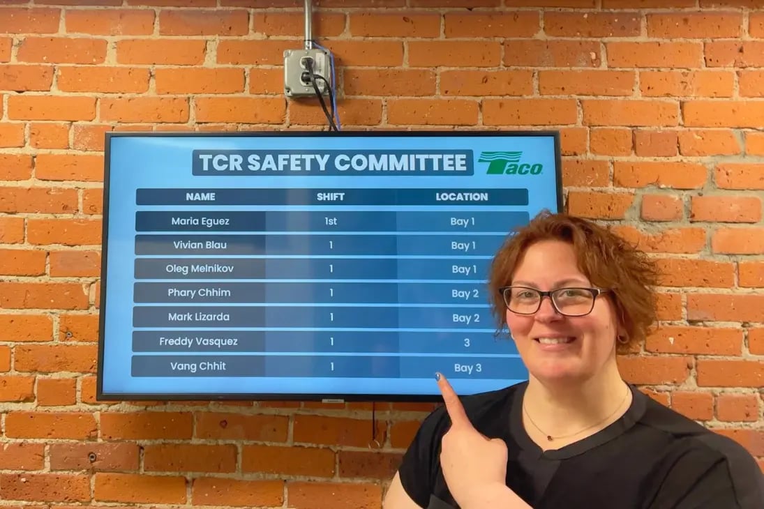 A femae standing in front of a digital display about TCR Safety Committee