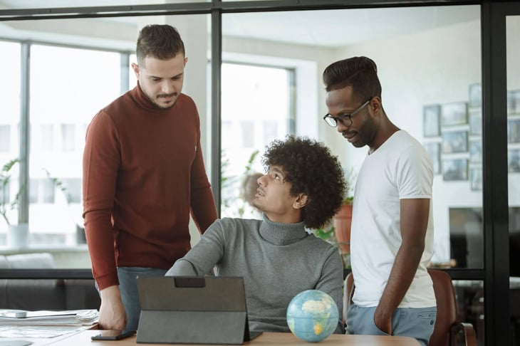 Three men working together and engaging with digital signage.