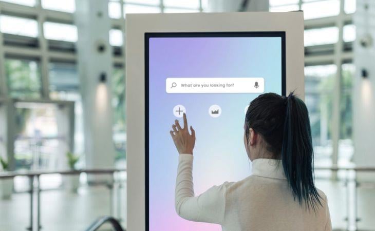 A woman navigating a touchscreen digital signage display.