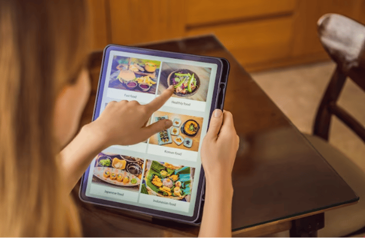 A woman ordering food on a tablet.