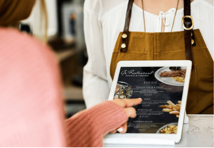 Person pointing at an item in a static digital menu board.