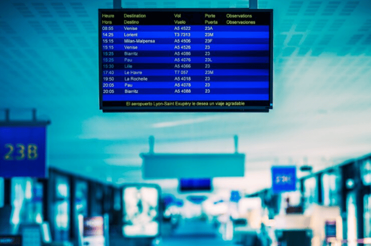 A dynamic digital poster at an airport showing flight details.