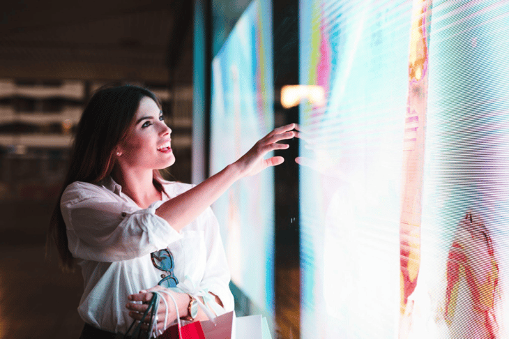 Woman touching a digital signage screen.