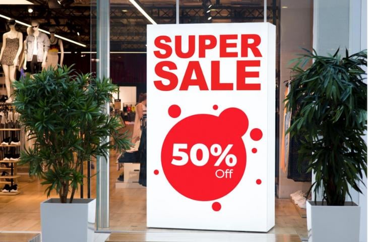 A large digital signage screen in front of a retail store announcing a sale.

 