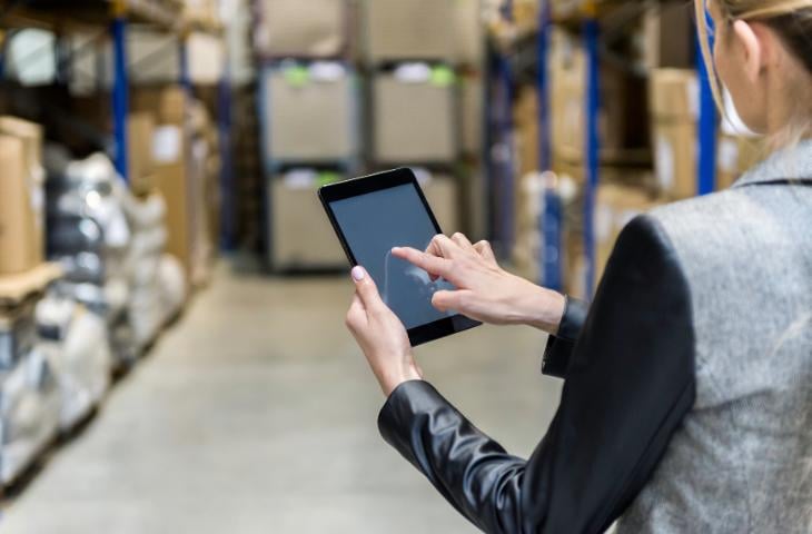 A warehouse worker reading training resources on a portable digital screen.