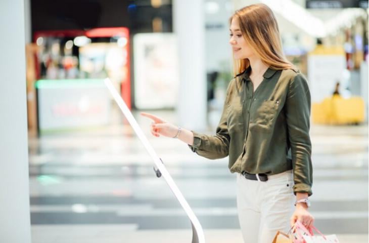 A woman interacting with a digital sign and inputting her interests.
