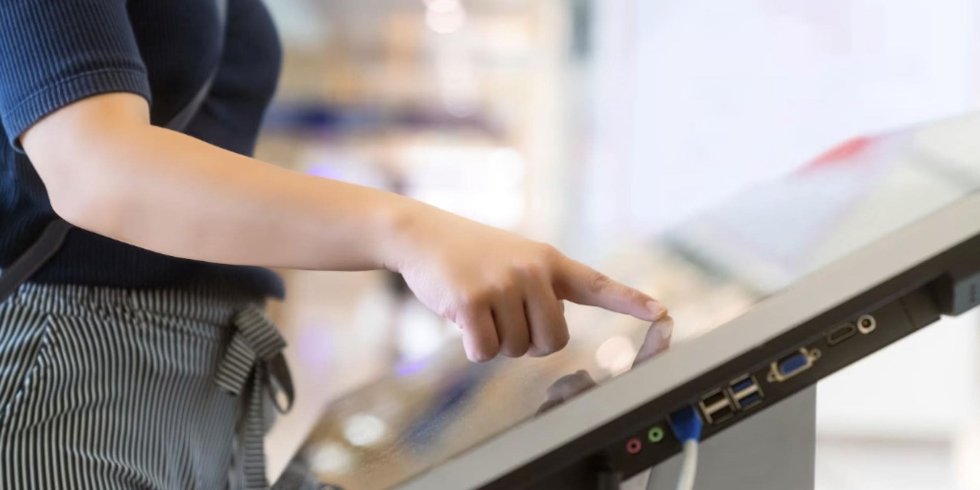 A woman tapping on the screen of a digital sign. 