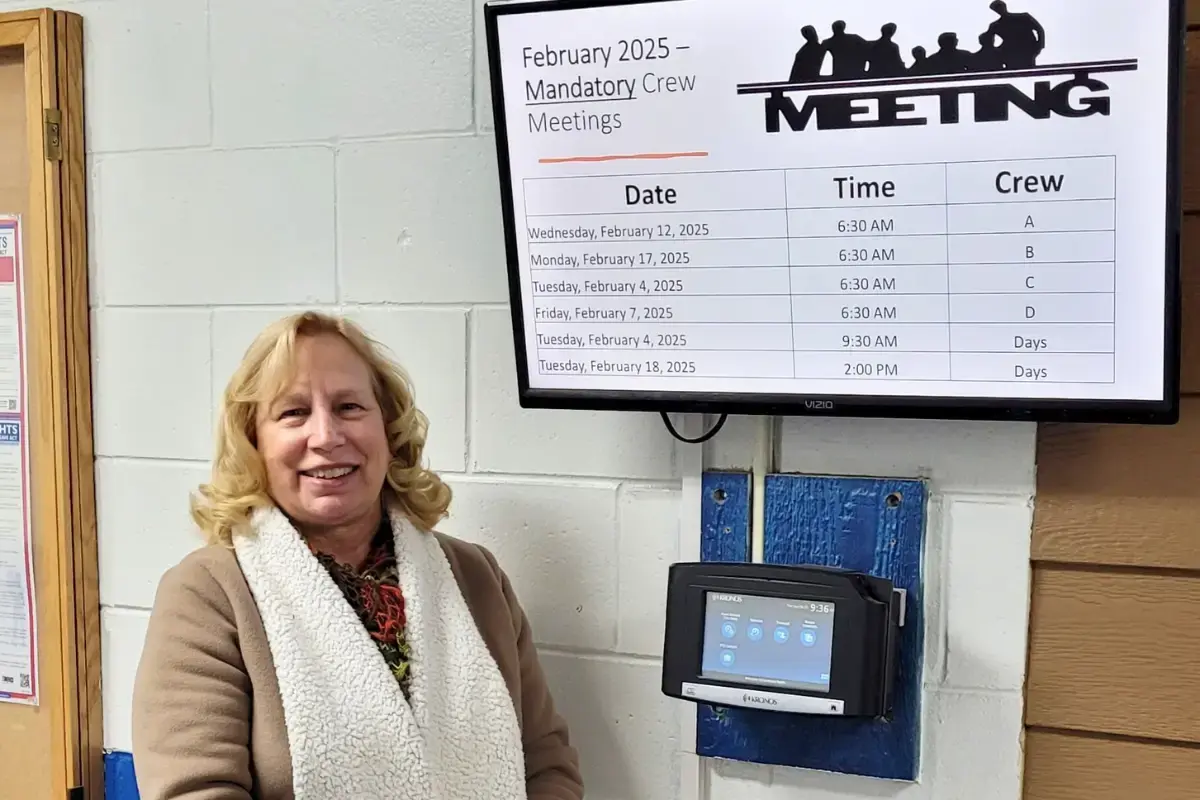 Roxan Reas standing next to a digital signage display