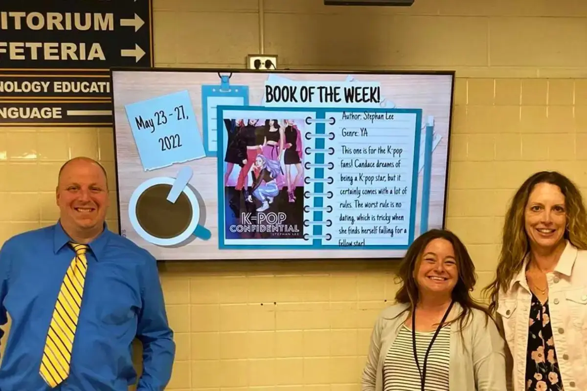 Three teachers standing in front of a digital signage display