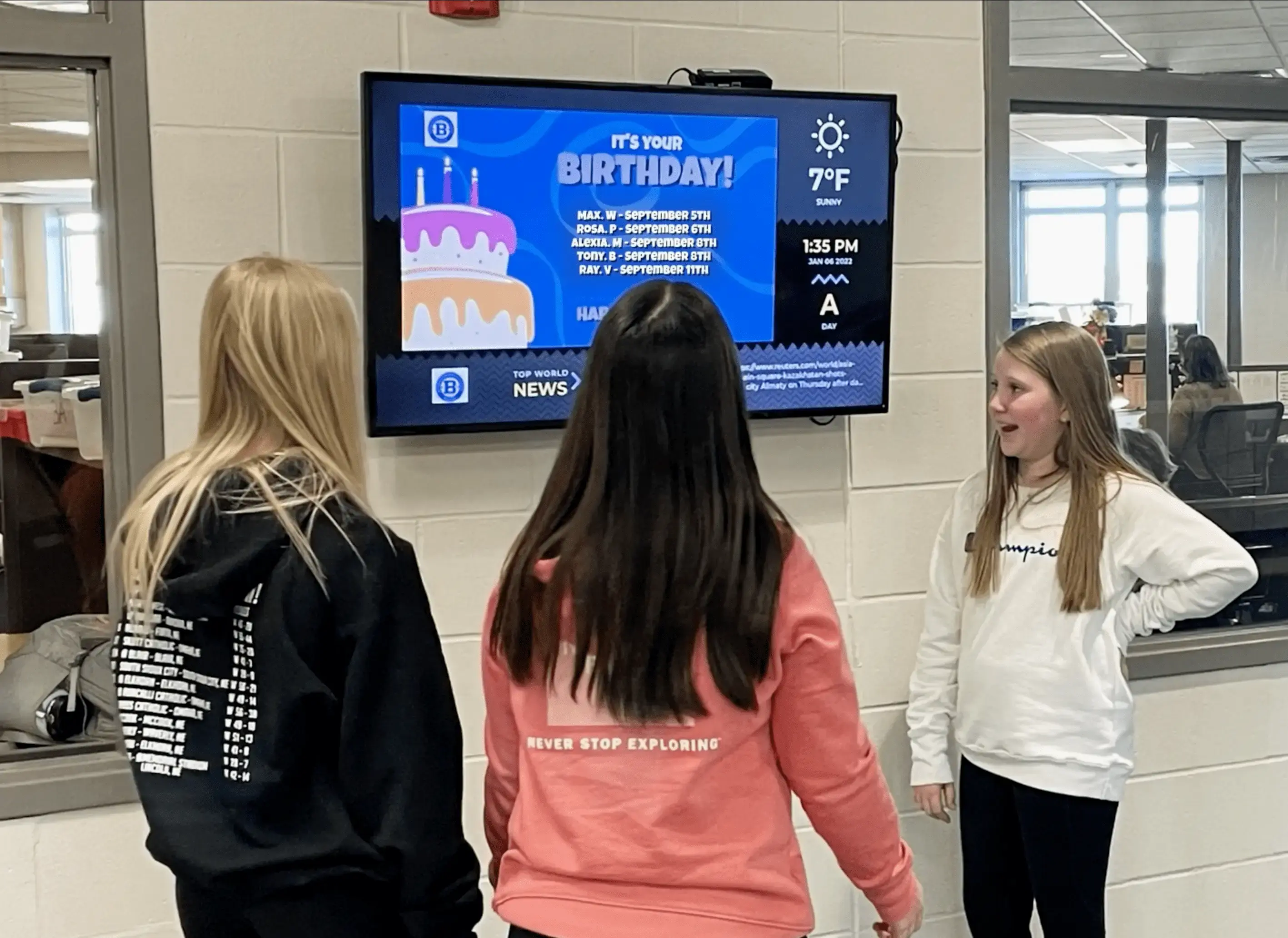 Three female students standing in front of a display